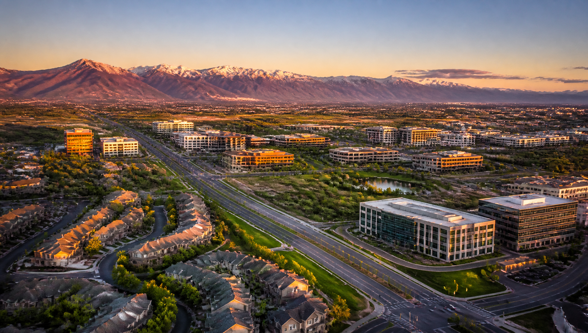 Aerial view of the Interlocken area in Broomfield, Colorado at sunset, with office buildings, residential rooftops, and the Front Range mountains in the distance