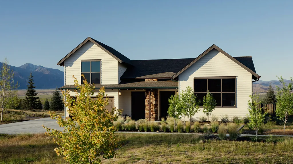 Two story prairie transitional home in Erie, Colorado with board and batten siding, a stone entry column, and native grass landscaping, with the Front Range foothills behind it